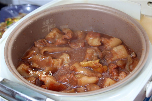 红烧猪头肉,用锅铲拌匀猪头肉,遮上电饭锅盖子,选择煲饭功能,坐等肉肉出锅