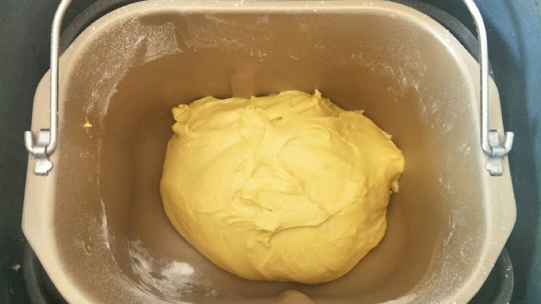 南瓜红豆排包,除黄油外的面团材料按先液体后粉类的顺序放入面包机,揉一个程序后加入软化的黄油揉到扩展阶段