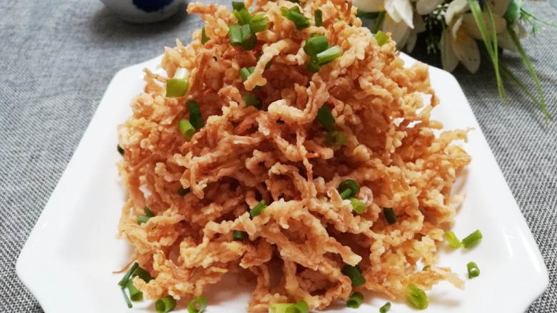 干炸金针菇,起锅装盘,撒上葱花。