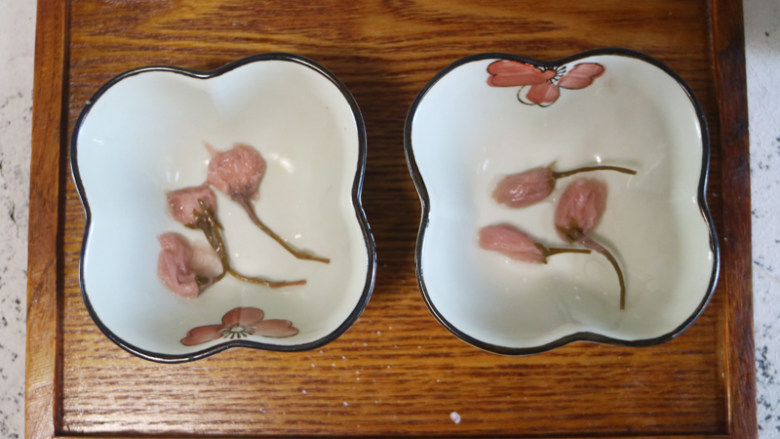 浪漫情怀樱花冻,磨具放上泡好的樱花,再将液体都搅拌均匀后倒入模具,放入冰箱冷藏 3 小时以上。