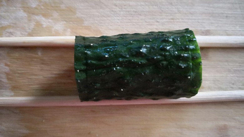 【翠竹报春】,先将黄瓜选一面为底部,用刨皮器将皮刨岀,作为装饰竹子用,接着将两根黄瓜切成八小段,用两根筷子夹住黄瓜,在两端半厘米处切一半,不要切断。