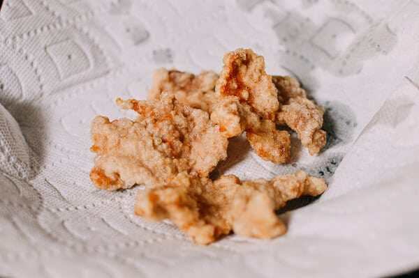 东北锅包肉,每批炸2分钟,把炸好的猪肉放到铁架上沥干。