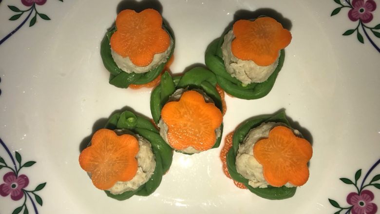 豇豆花环肉丸,将大花胡萝卜片放碟上,再依次放上豇豆花环、珍妮珍馐儿童鲜肉丸、小胡萝卜花片,下锅蒸5分钟