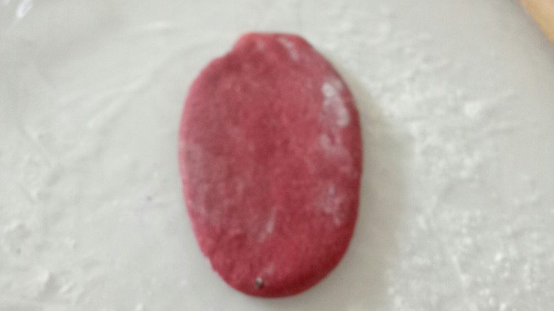 心花怒放手工椰蓉造型欧包,用手压扁,用擀面杖从中间朝上擀一下,再从中间朝下擀一下。