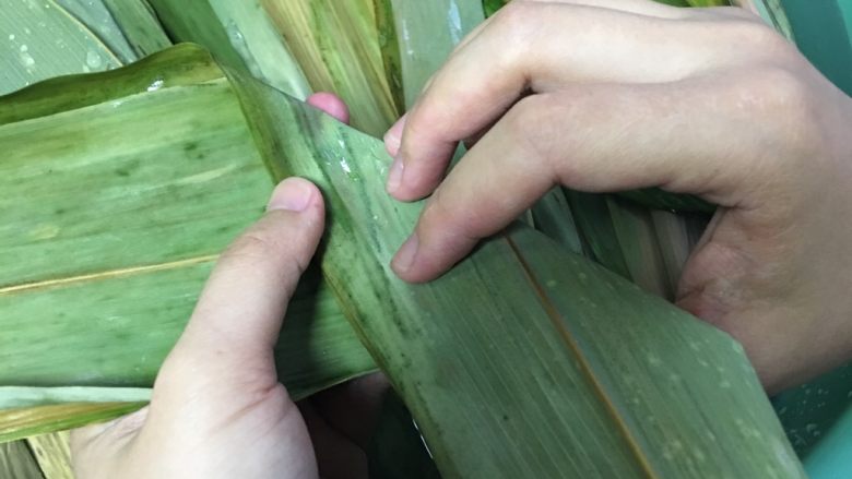 咸蛋黄肉粽,粽叶洗净,两片叠一起,先如图折一下