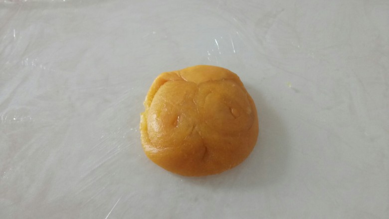 蔓越莓椰蓉酥,取一个,用母指从中间按一下,两头捏起,用手压扁。