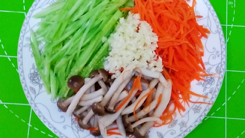 凉拌蟹味菇,将蟹味菇,黄瓜丝,胡萝卜丝放入盘中,上面放入蒜末