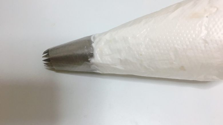 蛋白糖,我用的是十八齿裱花嘴,混合好的蛋白放入裱花袋收一下裱花袋顶部把蛋白统一挤压到裱花嘴底部。
