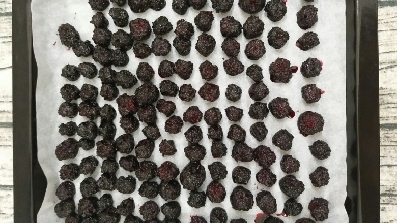 自制杨梅干,自己做更健康,把煮好的杨梅放入烤盘里。