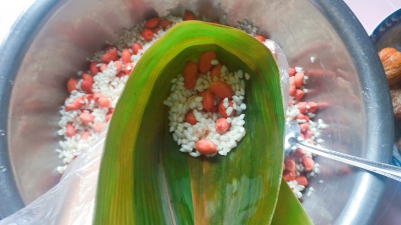 花生蜜枣粽,在漏斗中舀入1/3的花生糯米,拿筷子捅实;