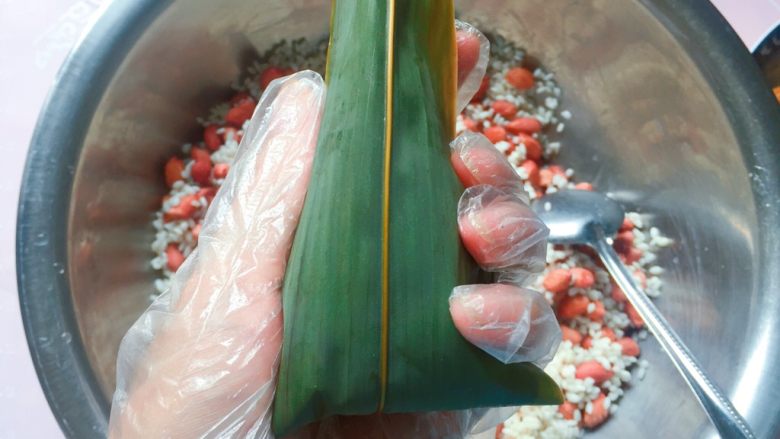 花生蜜枣粽,再把粽叶上端的叶子向下折,直到完全盖住开口的地方就好了;
