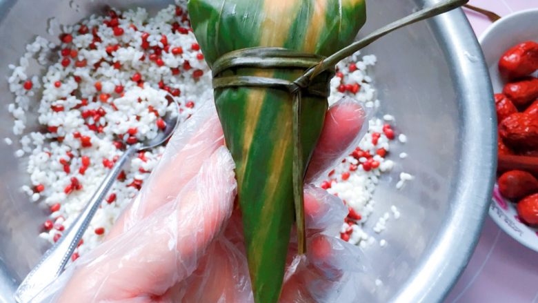 红豆红枣牛角粽,最后用粽绳扎紧打结,一个酷似牛角的粽子就完成啦。