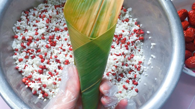 红豆红枣牛角粽,然后手捏住上面那一头粽叶转一圈,形成更长的牛角形状;
