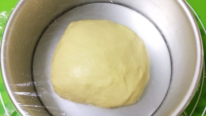 黄油肉松面包,整理滚圆,放入模具,盖上保鲜膜。