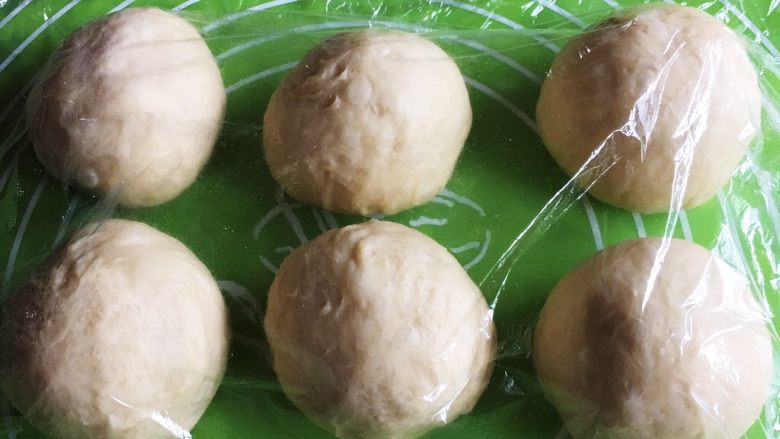 黄油肉松面包,滚圆,盖上保鲜膜静置20分钟。