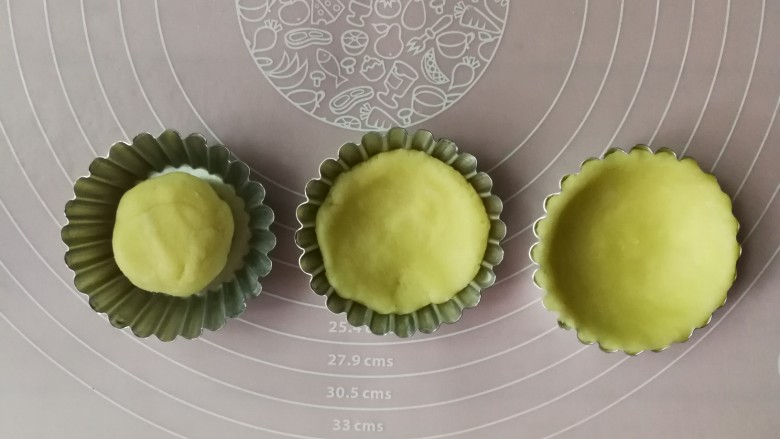 香酥椰挞,先把挞皮按扁,然后用双手拇指转圈不停按压并往上轻推面团,使面团贴合整个挞模