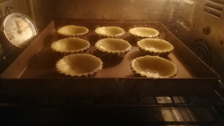 香酥椰挞,烤箱200度预热后,将挞皮送入烤箱中层烘烤,上下火180度8分钟