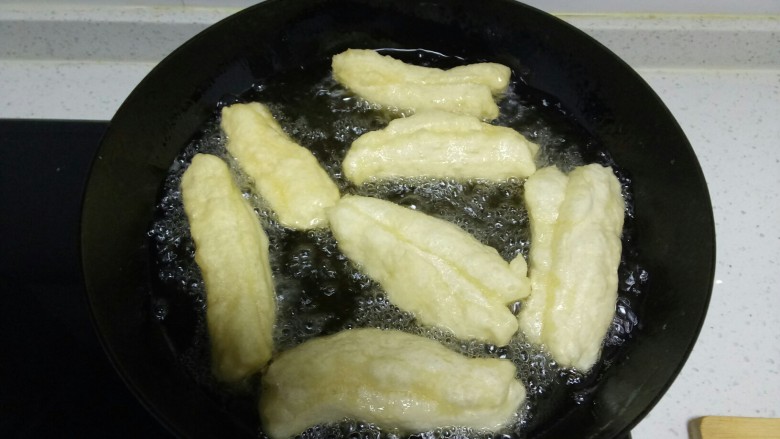 自制健康油条,早起,手上、案板上均匀抹油,将面搓成长条,用手拍扁,切成2指宽,2个合在一起。锅中倒入适量油,油热5层热下入油条,中小火炸。