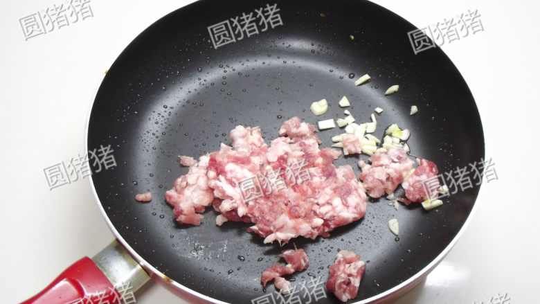 榄菜肉末炒豆角,锅内放入蒜头碎及猪绞肉,用小火煸炒至出油脂。