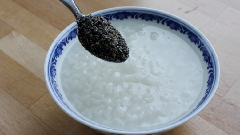 核桃仁芝麻糯米粥,将煮好的粥盛入各自的碗中散上芝麻粉和糖。