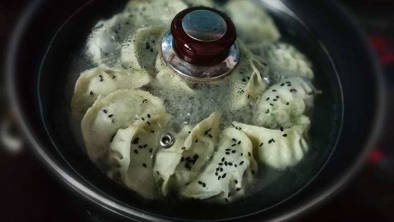 韭菜猪肉饺子,倒入一碗清水,盖上盖子小火焖煮至熟,快要收汁时撒上黑芝麻和葱花