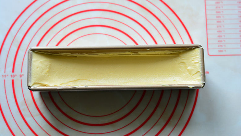 酸酸甜甜如云朵般口感的百香果磅蛋糕,搅拌好的面糊装入裱花袋中，挤入至磅蛋糕的模具里，用刮刀把面糊表面抹光滑，抹成两边高，中间低的状态。