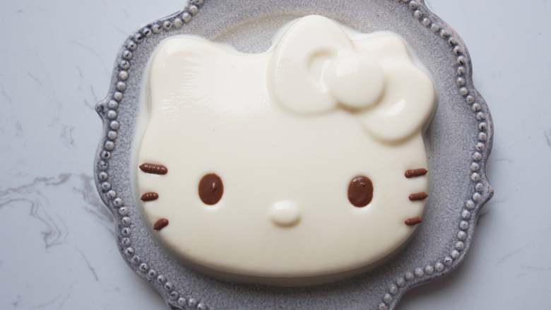 Hello Kitty牛奶冻,取出后将模具倒扣在盘子中,用吹风机吹一圈就脱模了。用融化的<a style='color:red;display:inline-block;' href='/shicai/ 874'>巧克力</a>画上眼睛和胡须就完成啦~