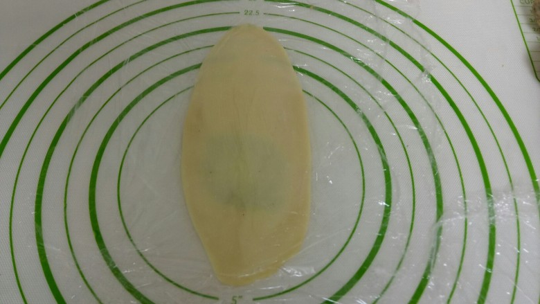 苏式椒盐月饼,盖上保鲜膜,用擀面杖从中间往上干,再从中间往下擀,擀成牛舌状。