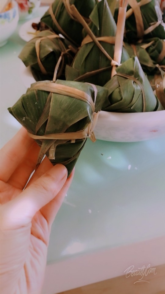 枣粽子,粽叶弯下来盖上米,用绳捆绑好。