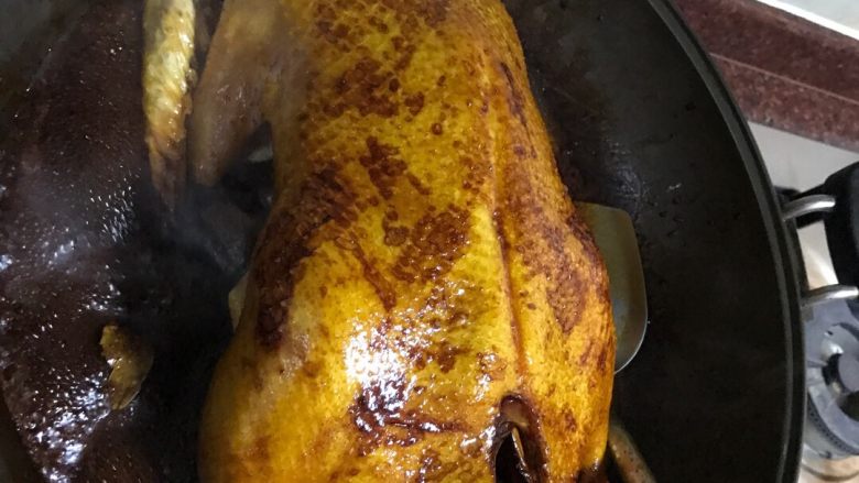 潮汕卤鸭,翻转后继续淋酱到鸭身上。