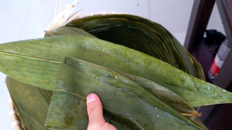 不同类型粽子的包法,再拿一张或两张粽叶,把前两张对折好的粽叶的一面包住。