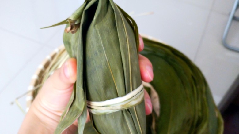不同类型粽子的包法,开始收口了,把粽叶捋顺,全部对折过来。用绳子绑紧。