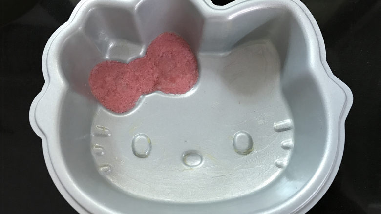 Hellokitty米蛋糕 ,先放入模具中蝴蝶结的地方,铺平后用手轻压一下。