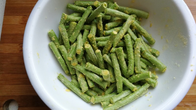 玉米面蒸豆角,接下来调入一点点食用油,把玉米面和豆角翻拌均匀,让豆角均匀沾满玉米面。