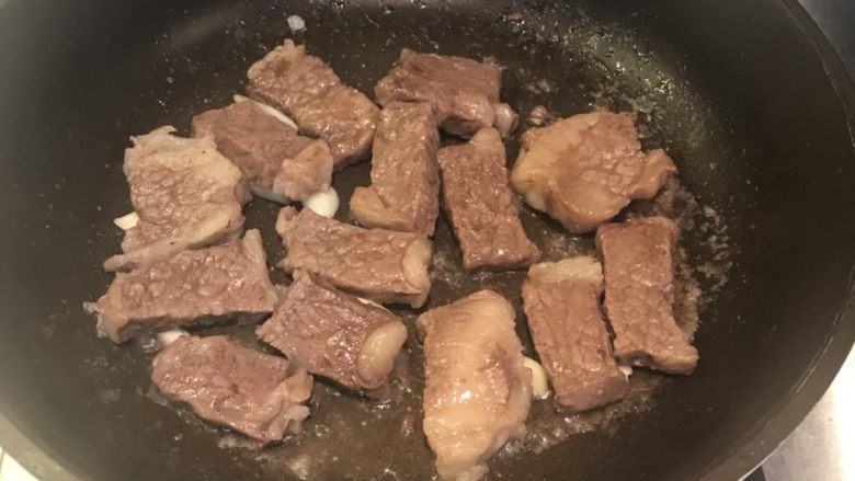煎牛排青椒,翻转把牛肉另一面压着蒜片,小火慢煎