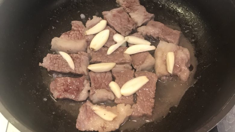 煎牛排青椒,然后在表面放入蒜片,盖上锅盖煎一下