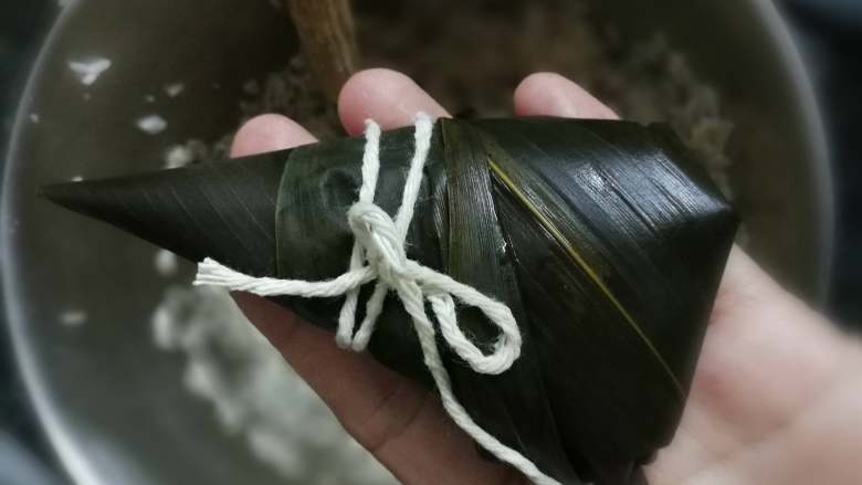 牛肉粽子,把上面的粽子叶折回来,包好粽子,用棉绳扎好