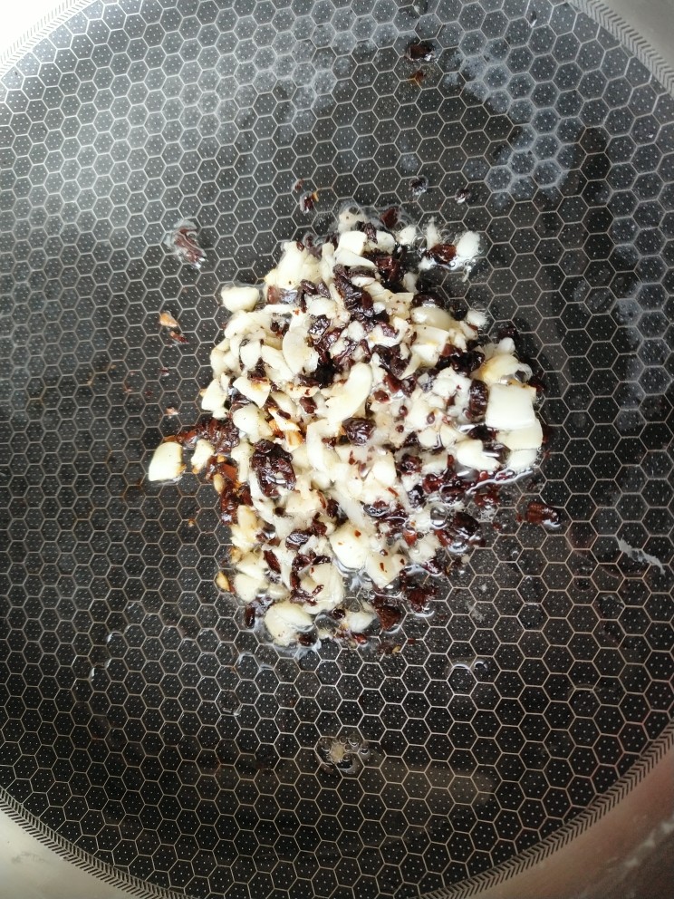 豉汁蒸滑鸡,锅内倒入食用油,爆香蒜瓣跟豆豉。