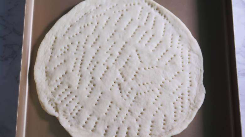 鲜虾鸡肉披萨,拿一个面团,擀圆,用叉子戳满小孔