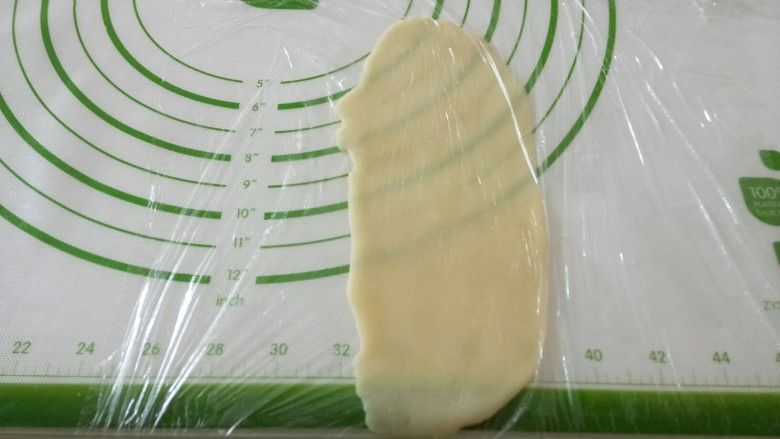 黑米馅老婆饼,收口朝下,用手压扁,从中间往上擀一下,再从中间往上擀一下,擀成牛舌状。