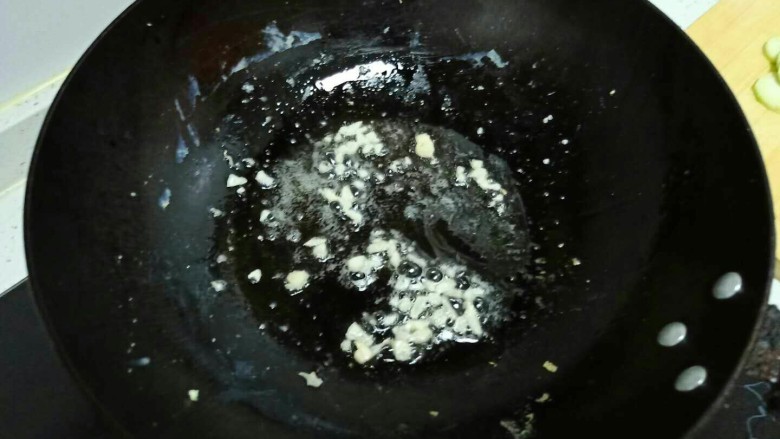 丝瓜炒鸡蛋拌黑米手擀面,锅中放入适量油，油热后倒入蒜末炒香。