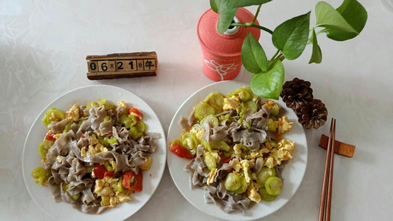 丝瓜炒鸡蛋拌黑米手擀面,面条中倒入菜，搅拌均匀。