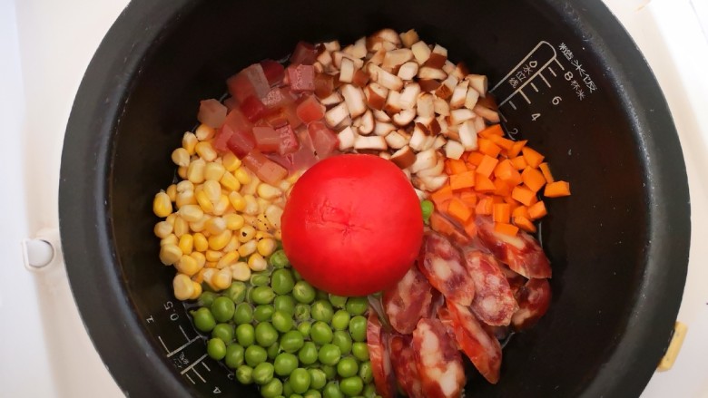 番茄焖饭,将备好的食材依次码在锅中的大米上，番茄放中间