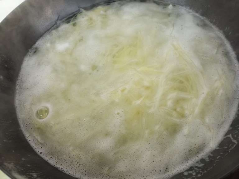 土豆丝拌洋葱丝,然后锅里烧开水,把土豆丝放进去焯水。