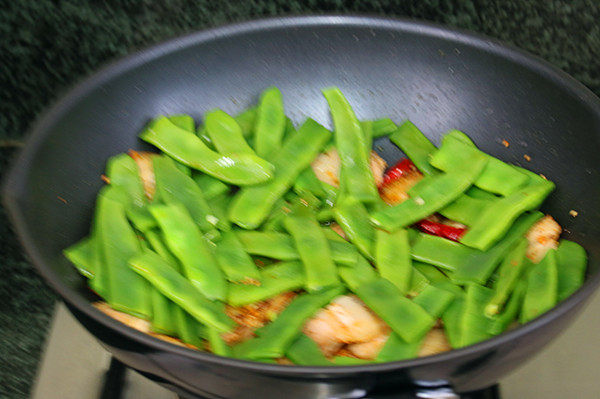 五花肉小酱炖扁豆,倒进扁豆和辣椒,撒点清水,翻炒均匀后遮上锅盖