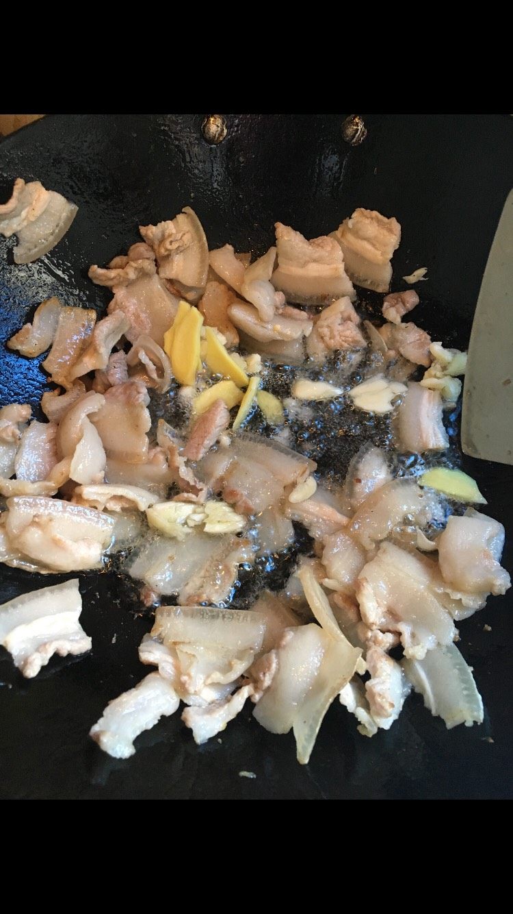 农家小炒肉,锅里放少许油，放肉片翻炒，炒至油出来，肉片变薄，放入姜片碎蒜头黄酒，继续翻炒。