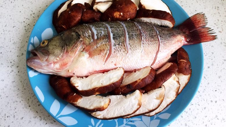 清蒸鲈鱼,雨两面切斜刀，让鱼肉更入味，蒸出来的鱼肉更嫩，把盐顺着切口往里抹匀，塞入几片生<a style='color:red;display:inline-block;' href='/shicai/ 37'>姜</a>到鱼腹腔内，香菇码到四周