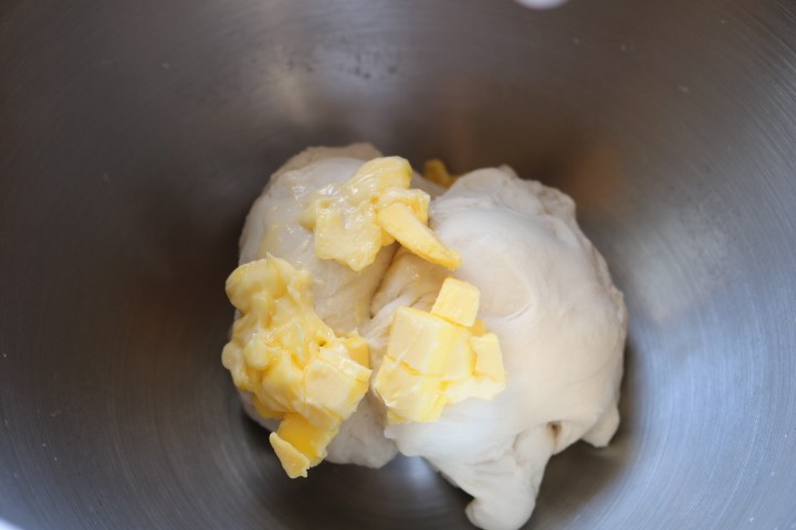 日式红豆包,用低档搅拌成团,中档揉至能拉出厚膜后加入室温软化的黄油。