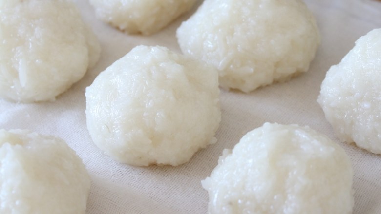 夹心豆沙糍糕,制作糍饭糕生坯:
手上沾点冷开水,将熟糯米饭分成若干等份,抓握捏紧;放在干净潮湿的布上。
注:手上沾水是为了防粘,用潮湿的布也是为了防粘。