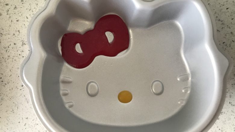Kitty 猫芒果椰奶千层糕,把粉色椰浆倒入小号裱花袋中,前端剪一个小口,把蝴蝶结部分填满,用小勺挖一点芒果泥,把猫嘴也填满,放入冰箱冷藏10分钟直至凝固。